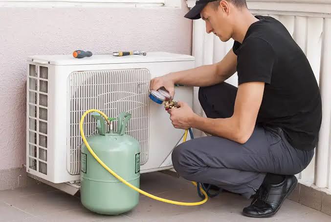 Technician checking pressure gauges beside a residential air conditioning unit