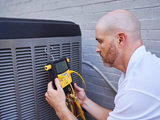 Technician checking an outdoor air conditioning unit with a digital meter