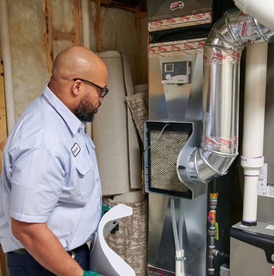 Technician inspecting an indoor furnace and connected metal ductwork