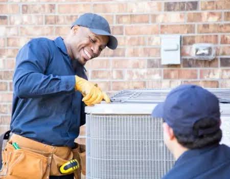 Two HVAC technicians inspecting a home air conditioning condenser