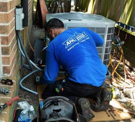 Technician working beside an outdoor HVAC condenser
